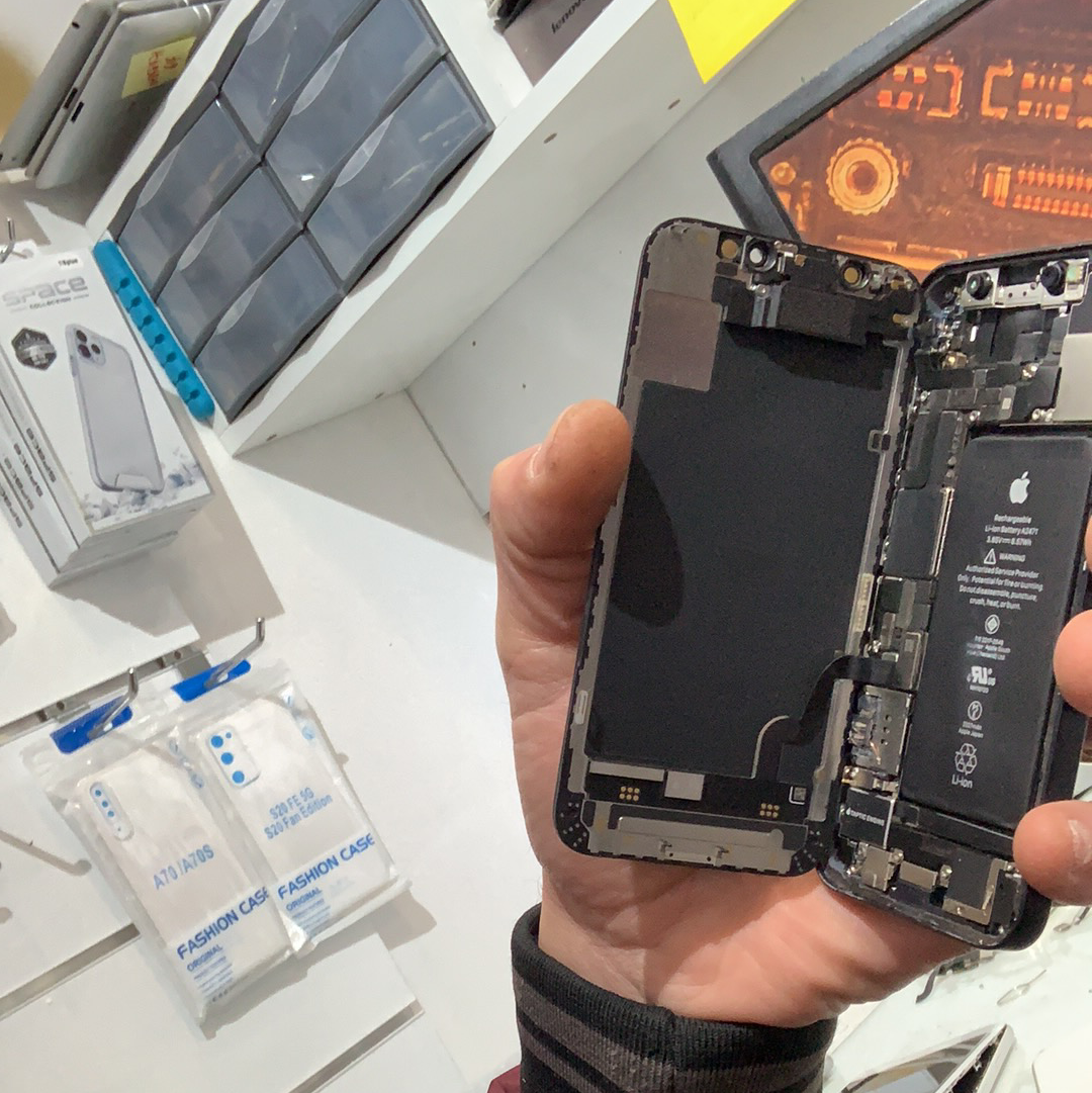 iPhone ouvert tenu sur le poste de réparation de SOS PHONE